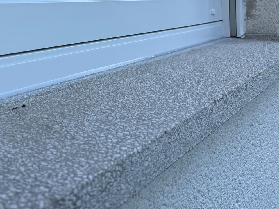 Unterer Anschluss eines neuen weißen Fensterrahmens an die steinerne Außenfensterbank