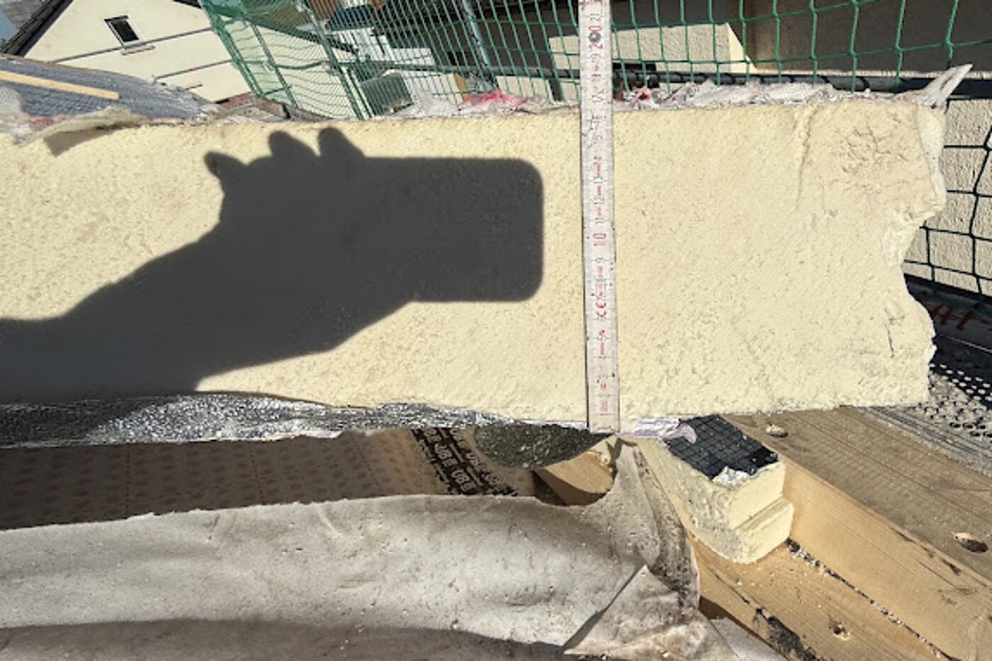 Aufsparrendämmung auf einem Steildach, die Stärke der Dämmplatte wird mit dem Zollstock gemessen
